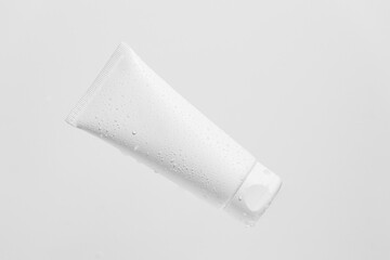 White mocap tube of face or body cream with water droplets on an isolated background. Cosmetics concept for care, beauty, aesthetics and advertising cosmetic products