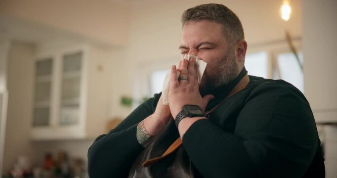 Sick, sneeze and man with tissue, allergies and sickness for cold symptoms or illness in kitchen. Chef, guy and virus with congested sinuses, toilet paper and fever with health issue and bacteria