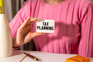 desk clock and notepad on the work desk. text TAX PLANNING