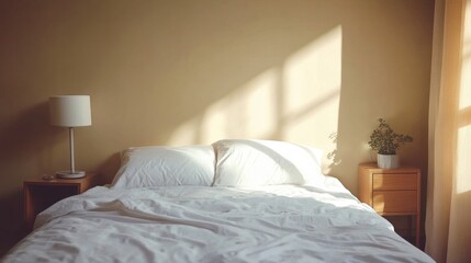 A bed in a minimalist room, with crisp white sheets, a single pillow, and a small bedside table with a lamp.