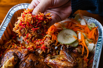 eating chicken kabsah with hand, mandi rice with pickle