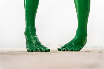 A close-up studio shot of a green, zombie-like foot isolated on a white background. The foot...