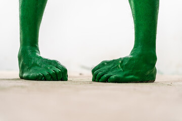 A close-up studio shot of a green, zombie-like foot isolated on a white background. The foot...
