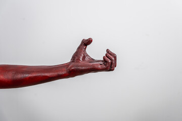 A terrifying red demon hand, reaching out menacingly on white studio background. The eerie,...