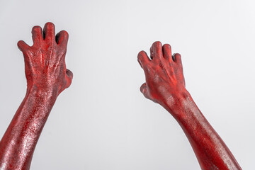 A terrifying red demon hand, reaching out menacingly on white studio background. The eerie, Halloween-themed image exudes horror, capturing the essence of fear, death, the undead in ghostly scene.