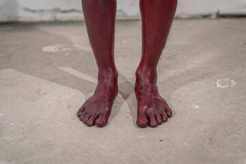 Dirty and horrifying red zombie feet displayed on white studio background. The gruesome...