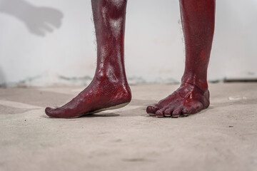 Dirty and horrifying red zombie feet displayed on white studio background. The gruesome Halloween-themed image emphasizes fear and shock, capturing the grotesque and unsettling nature of the undead.