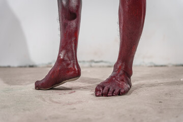 Dirty and horrifying red zombie feet displayed on white studio background. The gruesome Halloween-themed image emphasizes fear and shock, capturing the grotesque and unsettling nature of the undead.