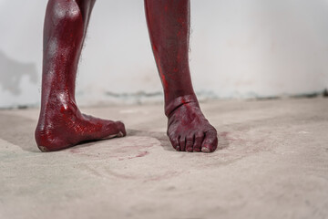 Dirty and horrifying red zombie feet displayed on white studio background. The gruesome Halloween-themed image emphasizes fear and shock, capturing the grotesque and unsettling nature of the undead.