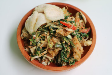 A plate of Lotek or traditional salad from Indonesia made from mixed vegetables such as spinach, cabbage, tomatoes, bakwan, with peanut sauce and cracker.