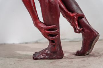 Dirty and horrifying red zombie feet displayed on white studio background. The gruesome Halloween-themed image emphasizes fear and shock, capturing the grotesque and unsettling nature of the undead.