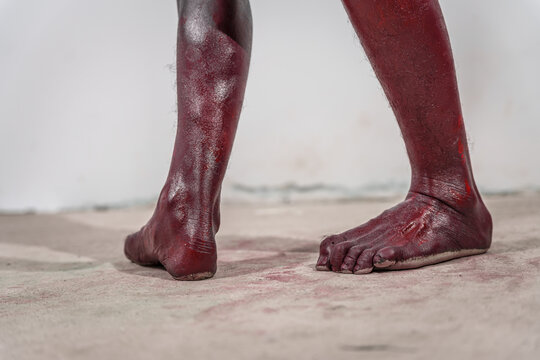 Dirty and horrifying red zombie feet displayed on white studio background. The gruesome Halloween-themed image emphasizes fear and shock, capturing the grotesque and unsettling nature of the undead.
