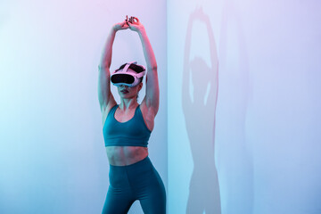 Woman in athletic wear uses VR headset while stretching indoors