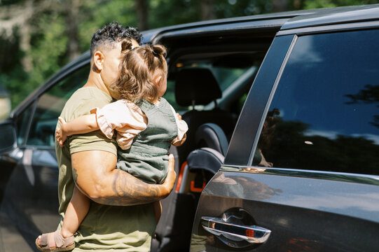 lgbtq woman and mother getting her toddler daughter into car seat