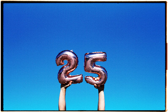 holding number-shaped balloons forming the number 25, 35mm