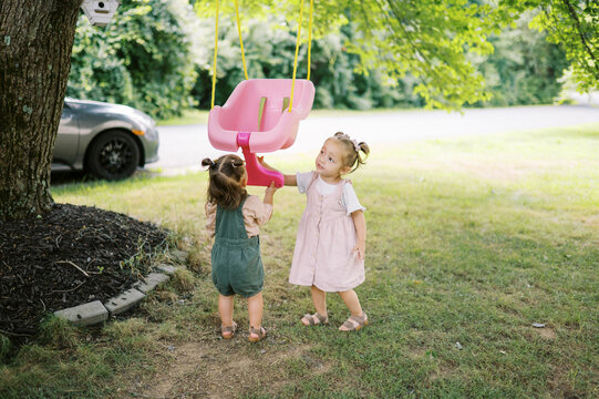 family with toddler children playing in yard with swingset