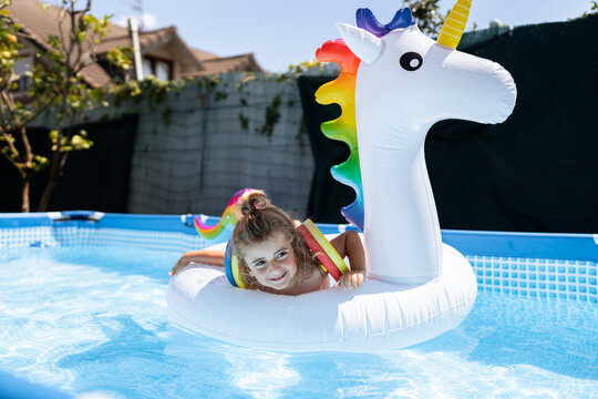 Little girl swimming and having fun with inflatable unicorn
