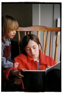 Brown-haired girl doing homework with her younger sister. Film