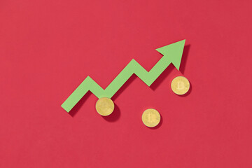 Green arrow pointing upwards with bitcoin coins on a red background,