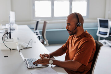 Customer service representative working on laptop in office