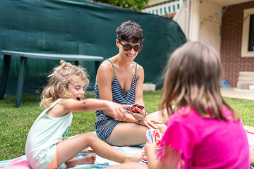 Mother and daughters playing cards in backyard having fun