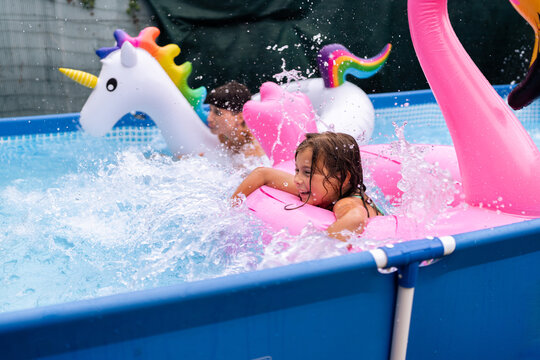 Children playing in inflatable pool having fun with water splashing