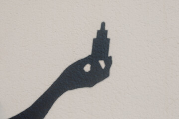 The shadow of an anonymous hand holding a dropper of a beauty product