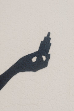 Silhouette of an unknown hand holding a dropper of a cosmetic product