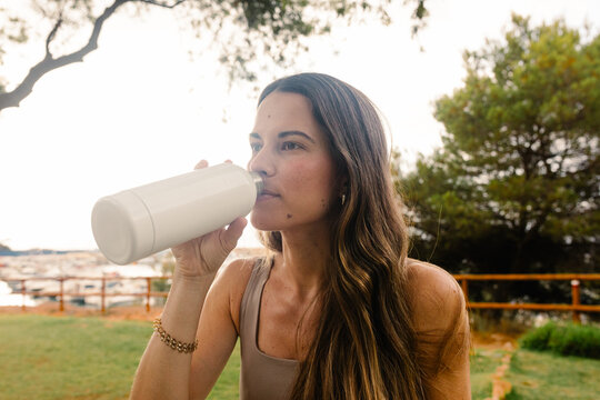 A fitness woman hydrates herself with water from a jerry can