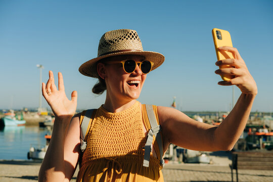 Woman waving hello while having video call during her summer vac