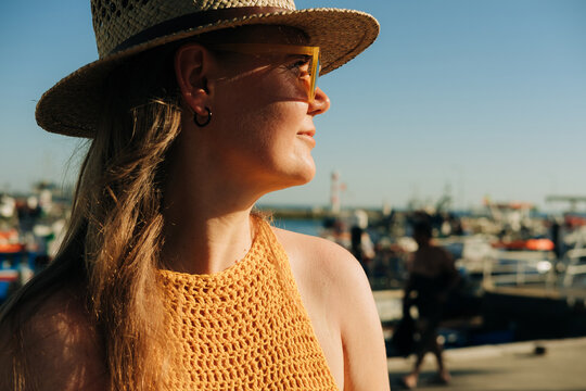 Smiling woman in a straw hat looking aside