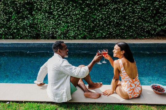 Couple enjoying wine by the pool on summer vacation