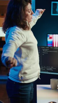 Vertical video Programmer doing software quality assurance, stretching arms behind back after reading source code, feeling fatigued. IT expert takes break from work to relax muscles after inspecting