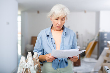 Stressed mature woman homeowner examining room under reconstruction, having problems with documents...