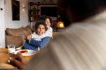 Playful sister embracing brother during breakfast