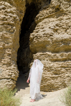 man wearing white veil standing near rock formation