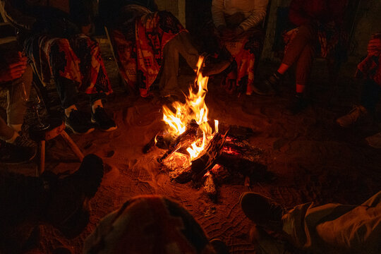 The blanket covered legs of safari tourists around the camp fire 