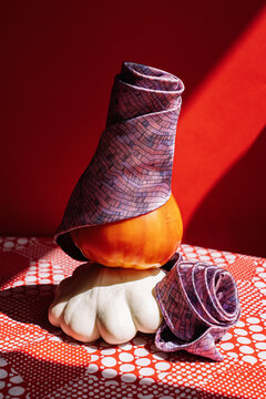 A Purple Tie Wrapped Around a Squash on a Red Tablecloth.