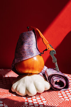 Purple Necktie Wrapped Around Pumpkin and tomato on Red Tablecloth.