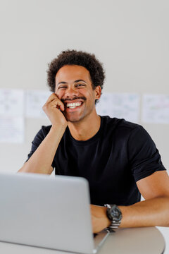Professional smiling while working on laptop at desk