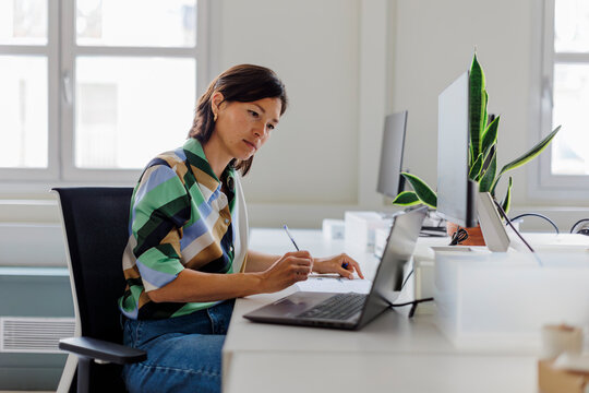 Focused professional woman working on laptop in modern office