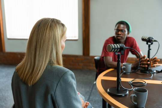 A man and a woman record a podcast