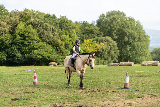 Young horse rider practicing show jumping in riding school paddock