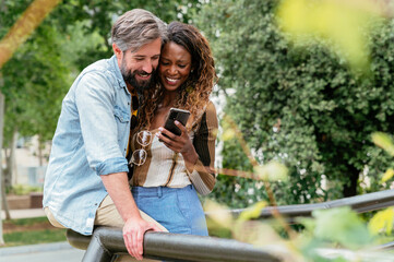 Joyful couple sharing a moment over smartphone in park