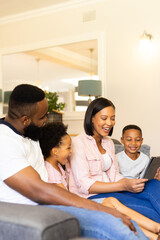 Fototapeta premium Family sitting on couch, smiling and using tablet together at home, copy space