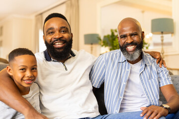 Smiling family of three generations sitting together on couch at home