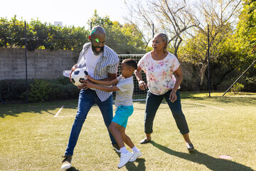 Obraz premium Playing soccer in backyard, grandparents and grandson enjoying outdoor time together
