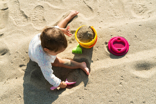 Little kid sitting on the beach, playing with sand 