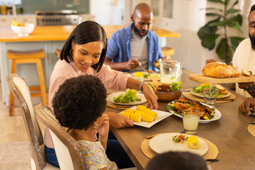 multigenerational family enjoying dinner together, serving corn and salad at home dining table