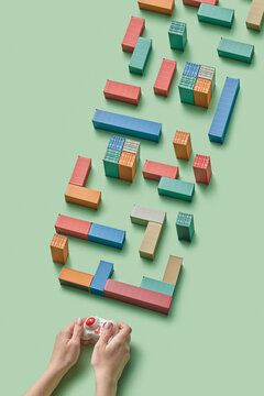 Cropped hands holding game controller in front of cargo containers